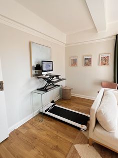 a living room with a treadmill on the floor and a desk in the corner