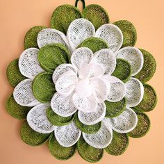 a green and white flower hanging on the wall