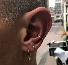 a close up of a person with ear piercings on their ears and in front of a city street