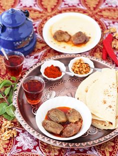 an assortment of food is on a plate with cups and sauces next to it