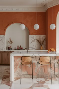 an orange and white kitchen with two stools in front of the bar area,