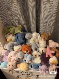 a pile of stuffed animals sitting on top of a table next to a curtain in a room