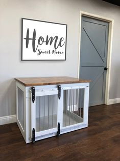 a white dog crate sitting in front of a sign that says home sweet home on the wall