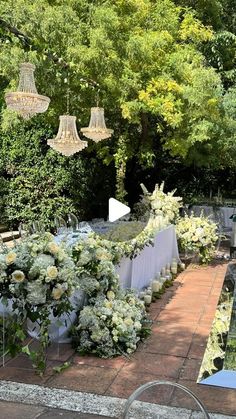 an outdoor dining area with tables, chairs and chandelier hanging from the trees