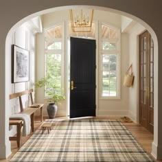 an archway leading to a foyer with a rug on the floor and a black door