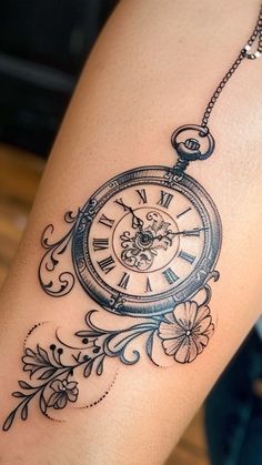 a woman's arm with a clock and flowers tattoo design on the side of her leg