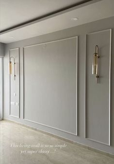 an empty room with white walls and two gold sconces hanging on the wall