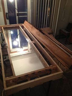 a wooden table with glass top in front of a window and some wires on the floor