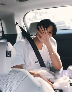 a woman sitting in the back seat of a car talking on a cell phone while holding her hand up to her face