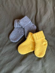 three knitted baby mittens laying on top of a bed next to each other