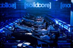 there are many people laying on their stomachs in the room with blue lights above them