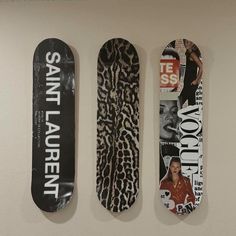 three skateboards are hanging on the wall with different designs and words painted on them