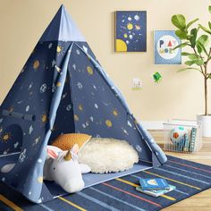 a child's teepee tent is set up on the floor in front of a potted plant