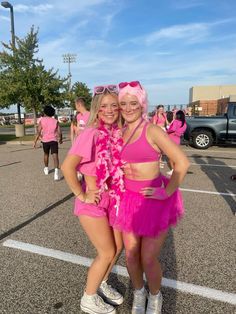 two young women in pink outfits posing for a photo on the parking lot with their arms around each other