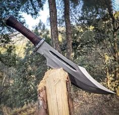 a knife that is sitting on top of a piece of wood in the middle of a forest