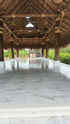 the inside of a building with white marble floors and straw roofing on top of it