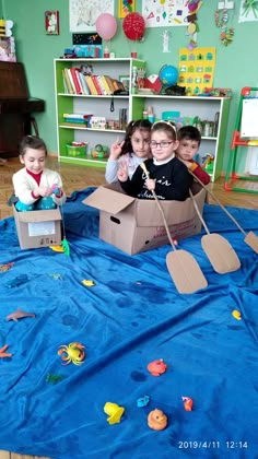 three children are playing in a cardboard boat