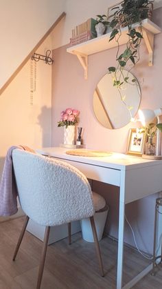 a white desk topped with a mirror next to a potted plant and a chair