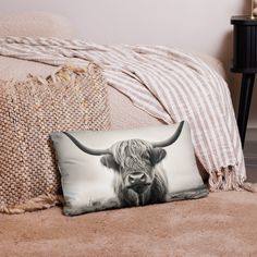 a black and white photo of a long horn bull pillow on a bed with a blanket