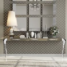 an elegant console table with mirrors on the wall and flowers in vases next to it