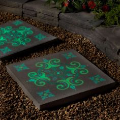 two black and green tiles sitting on top of gravel