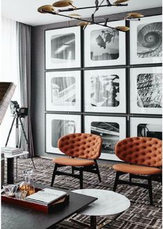 a living room with pictures on the wall and chairs in front of it, along with a coffee table