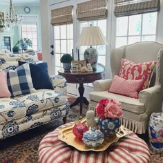 a living room filled with lots of furniture next to a window covered in curtains and pillows