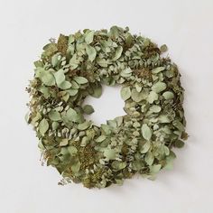 a wreath made out of green leaves on a white wall