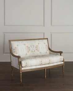 an old fashioned couch sitting on top of a hard wood floor next to a white wall