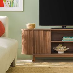 a flat screen tv sitting on top of a wooden cabinet next to a white couch