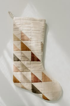 a quilted stocking hanging on the wall with a white background and shadow coming from it