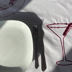 a white plate and silverware sitting on top of a tablecloth with red designs