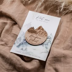 a wooden brooch sitting on top of a bed next to a brown blanket and a book