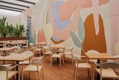 the interior of a restaurant with wooden tables and chairs, painted in pastel colors