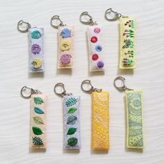 six keychains with different designs on them sitting on top of a white surface