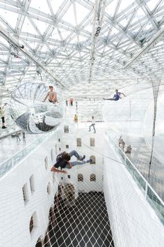 people are walking around in an indoor area that looks like a futuristic building with glass walls