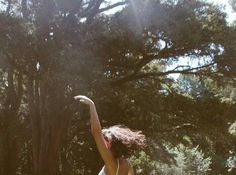 a woman is throwing a frisbee in the air with her arms outstretched to catch it