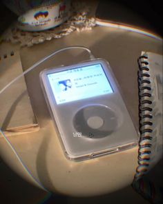 an ipod sitting on top of a table next to a notebook