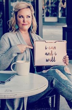 a woman sitting at a table holding up a sign