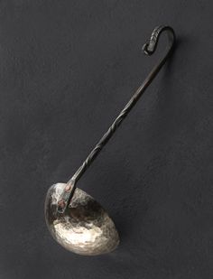 an old metal umbrella hanging from a hook on a black wall with a long handle