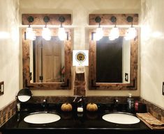 two sinks and mirrors in a bathroom with lights on the wall above them are decorated with pumpkins