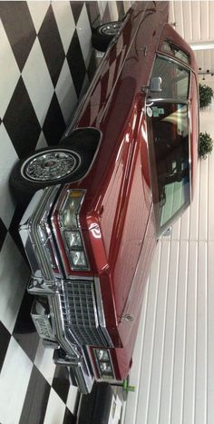 a red car parked in a garage next to a black and white checkered floor