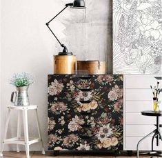 a black and white floral print cabinet next to a table with two vases on it