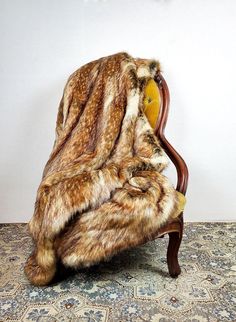 a chair covered in fur sitting on top of a carpet next to a white wall