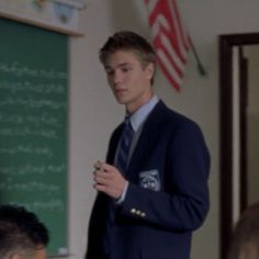 a young man standing in front of a chalkboard