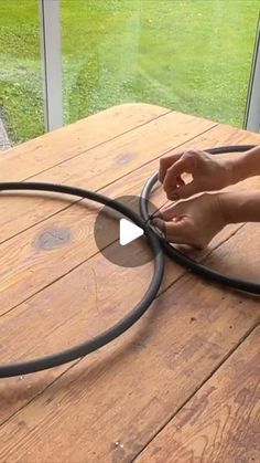 a person using a hose to clean a wooden table with glass doors in the background