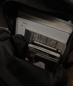 an open book bag filled with books on top of a wooden floor