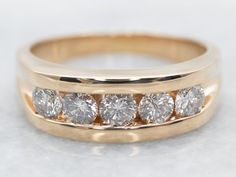 Channel settings never go out of style! The effect of one long row of diamonds, one band of glittering bright light, across the finger is always popular and always lovely. The sides of the ring completely encase the diamonds, keeping them safe and secure, which makes these rings easy to wear every day! Metal: 14K Yellow GoldGem: 5 Diamonds totaling 1.00 Carats, I1 in Clarity, H in ColorWidth of Band: 7.0 mmHeight off Finger: 3.4 mmRing Size: 10.25Marks: “14K” Stamped on the inside band White Gold Sapphire Ring, Gold Sapphire Ring, Gold Diamond Band, Gold Diamond Engagement Rings, Pearl And Diamond Ring, White Gold Sapphire, White Gold Wedding Bands, Right Hand Rings, Engagement Bands