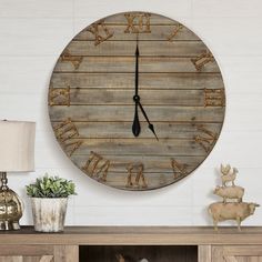 a large wooden clock mounted to the side of a wall next to a lamp and potted plant