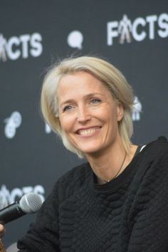 a smiling woman holding a microphone in front of a black backdrop with the words fact's on it